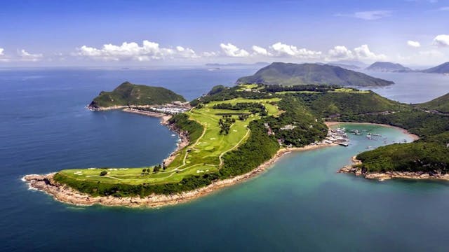 Aerial view of golf course on island surrounded by ocean