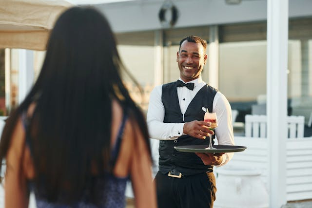 Waiter passing martini to customer