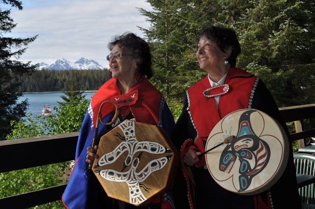 2 women in traditional clothing holding traditional drums