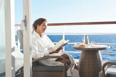 Woman reading a book on balcony of Oceania Insignia ship