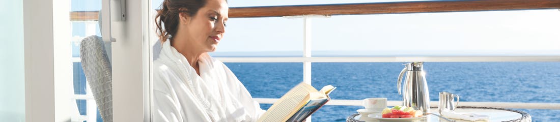 Woman reading a book on balcony of Oceania Insignia ship