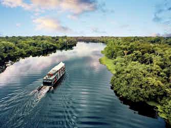 ship sailing in amazon - aqua expeditions