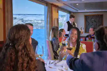 Group toasting with wine in a river cruise dining room, smiling woman in yellow