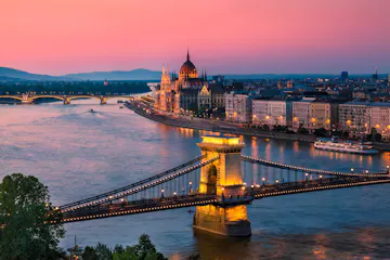 Illuminated Chain Bridge over the Danube with Hungarian Parliament and riverside buildings at sunset