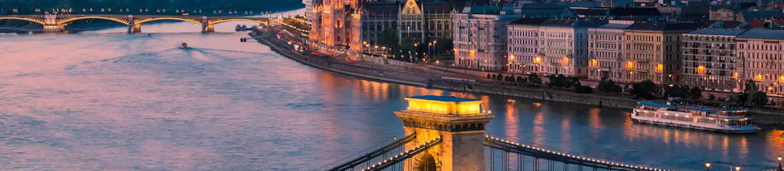 Illuminated Chain Bridge over the Danube with Hungarian Parliament and riverside buildings at sunset