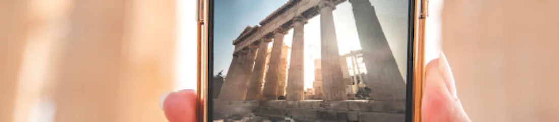 Hand holding smartphone capturing ancient temple columns visible on phone screen