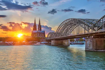 Sunset over Cologne: Hohenzollern Bridge over the Rhine with Cologne Cathedral silhouette.