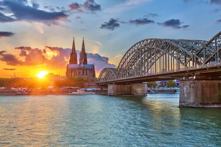 Sunset over Cologne: Hohenzollern Bridge over the Rhine with Cologne Cathedral silhouette.