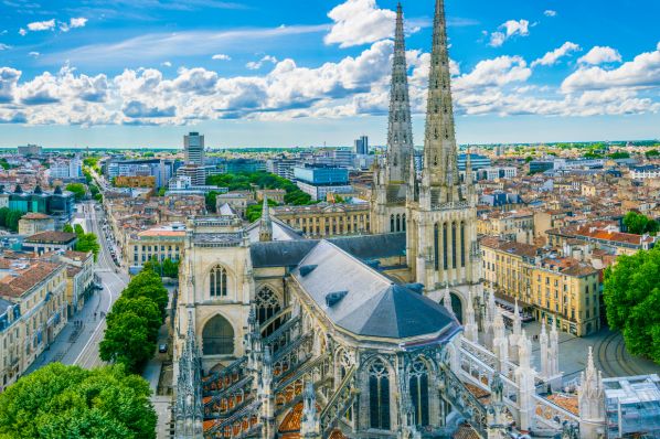 Aerial view of Gothic cathedral with twin spires overlooking city grid and tree-lined streets