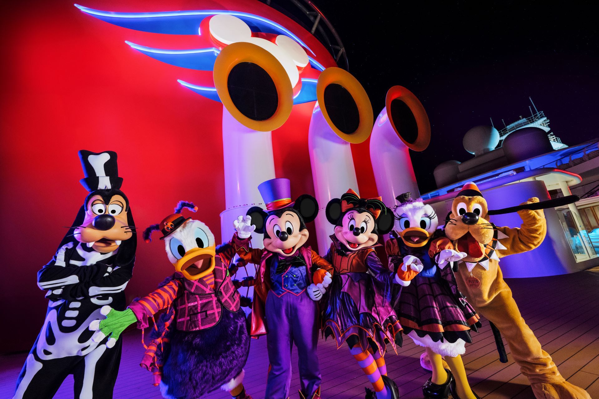 Mickey, Minnie, Donald, Daisy, Goofy and Pluto in Halloween costumes on a Disney cruise deck
