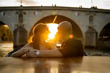 Romantic couple in boat embracing at sunset under a stone bridge arch