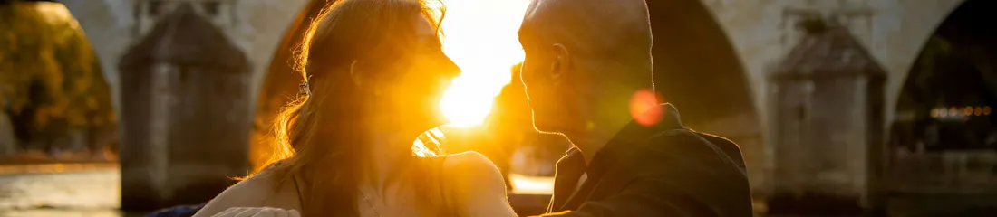 Romantic couple in boat embracing at sunset under a stone bridge arch