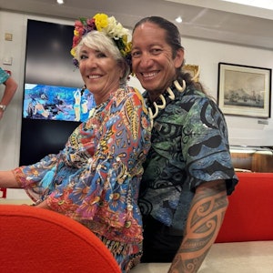 Smiling couple in colorful patterned clothing, woman with flower crown, man with tribal tattoo