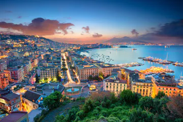 Twilight panorama of Naples bay with lit city, marina, and Mount Vesuvius silhouette