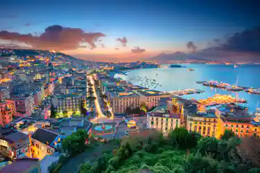 Twilight panorama of Naples bay with lit city, marina, and Mount Vesuvius silhouette