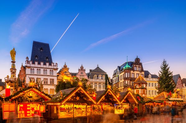 Evening Christmas market with illuminated wooden stalls, decorated firs and historic town buildings