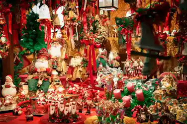 Christmas market stall crowded with Santa figurines, ornaments, wreaths, candles, red ribbons