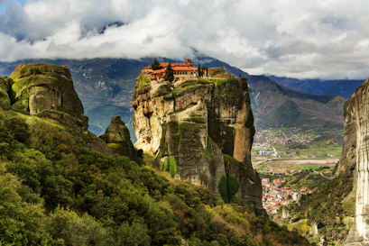 Red-roofed monastery atop a steep sandstone pillar overlooking green valley and town