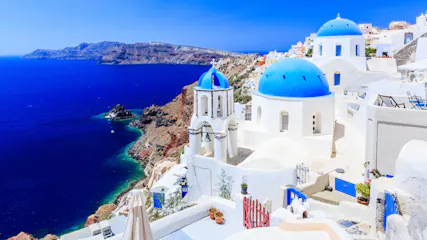 Oia, Santorini white cliffside buildings and blue-domed churches overlooking deep blue Aegean Sea