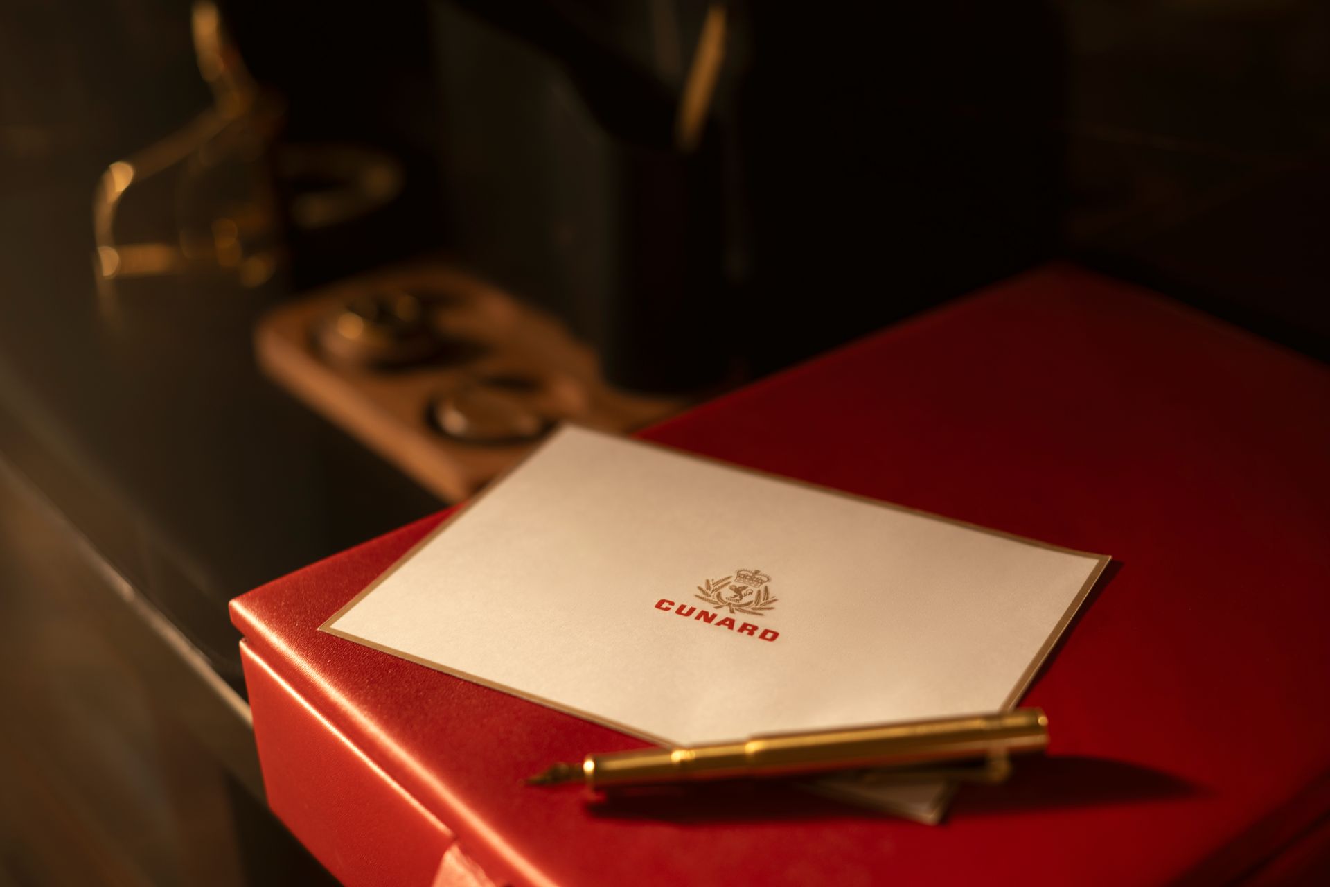 Cunard card on red box with gold pen and vintage ship telegraph in background