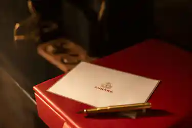 Cunard card on red box with gold pen and vintage ship telegraph in background