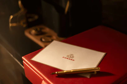 Cunard card on red box with gold pen and vintage ship telegraph in background