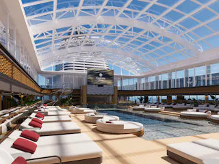 Indoor pool atrium with central pool, round daybeds and red-pillow sunbeds under glass dome