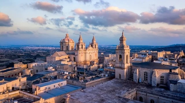 Aerial view of a historic city with baroque cathedral domes and bell towers at sunset