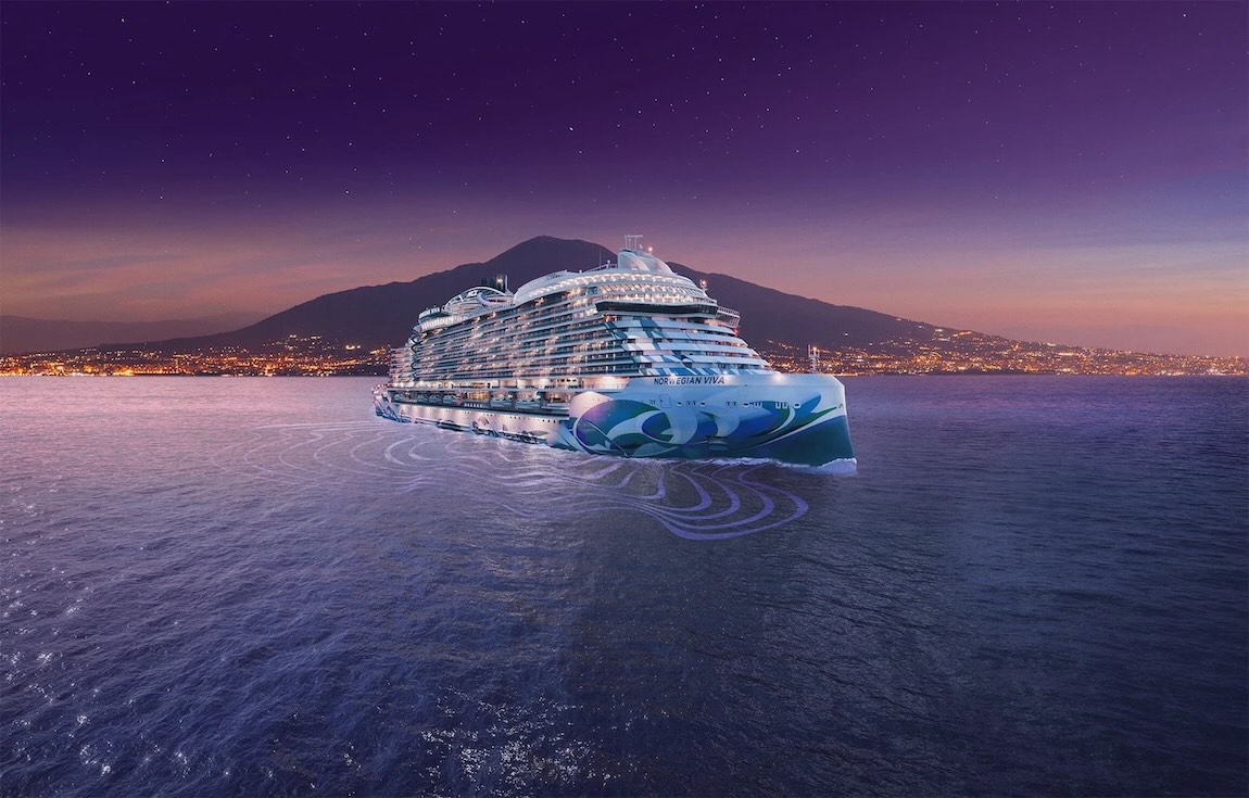 Illuminated Norwegian Viva cruise ship at dusk, sailing past coastal city with mountain and stars.