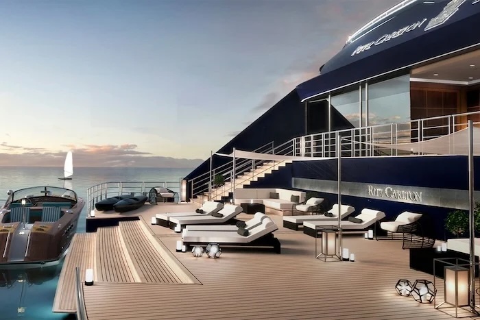 Ritz-Carlton yacht deck at sunset with sunbeds, lounge chairs, stairs and a tender boat