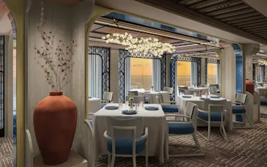 Upscale ocean-view dining room with white-tablecloth tables, blue chairs, terracotta vase