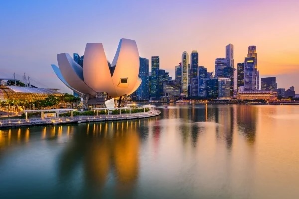 Lotus-shaped ArtScience Museum and Singapore Marina Bay skyline at sunset reflected in water