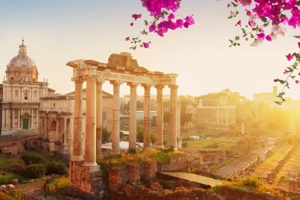 Ancient Roman Forum columns and ruins at sunrise framed by pink bougainvillea