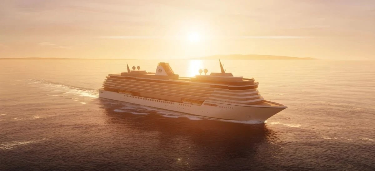 Large white cruise ship named Crystal sailing at sunset across calm open sea