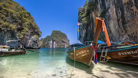 Thai long-tail boats moored in clear turquoise water amid limestone cliffs