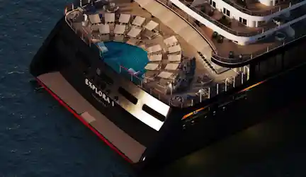 Aft deck of luxury ship EXPLORA I with circular pool, sun loungers and tiered decks at sea.