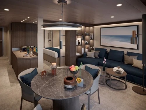 Contemporary suite with round marble dining table, navy sofa, bed alcove and kitchenette.