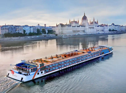 River cruise ship passing the Hungarian Parliament building on the Danube at dusk