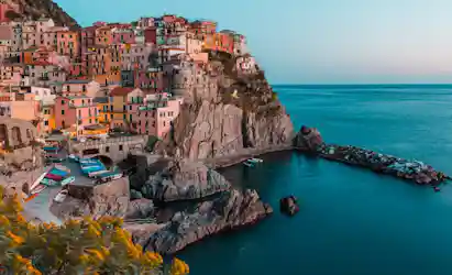 Mediterranean cliffside village with colorful stacked houses above a rocky harbor and small boats