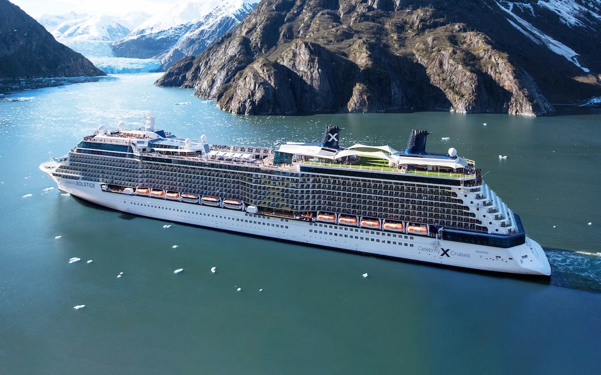 Celebrity cruise ship sailing in a glacier fjord with floating ice and steep mountains