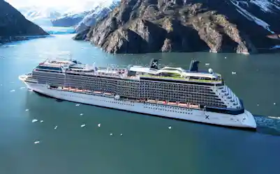 Celebrity cruise ship sailing in a glacier fjord with floating ice and steep mountains