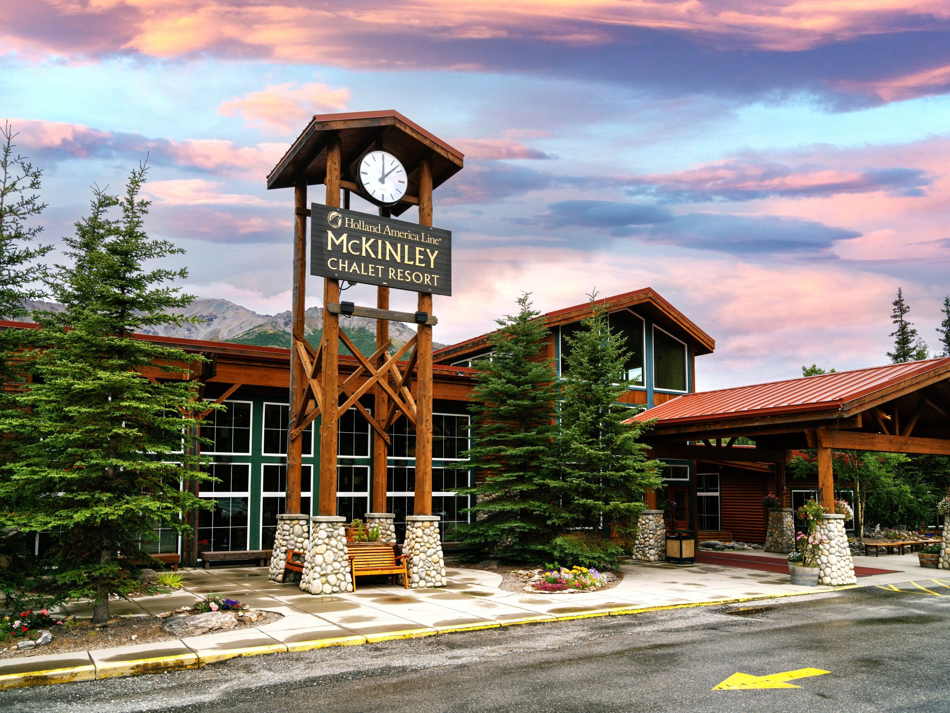McKinley Chalet Resort wooden clock tower and entrance with evergreen trees at sunset.