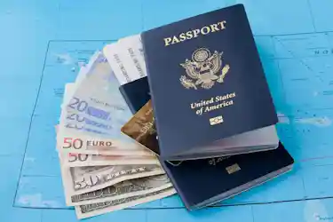 Two United States passports with boarding passes, euros and dollars fanned on a blue map for travel