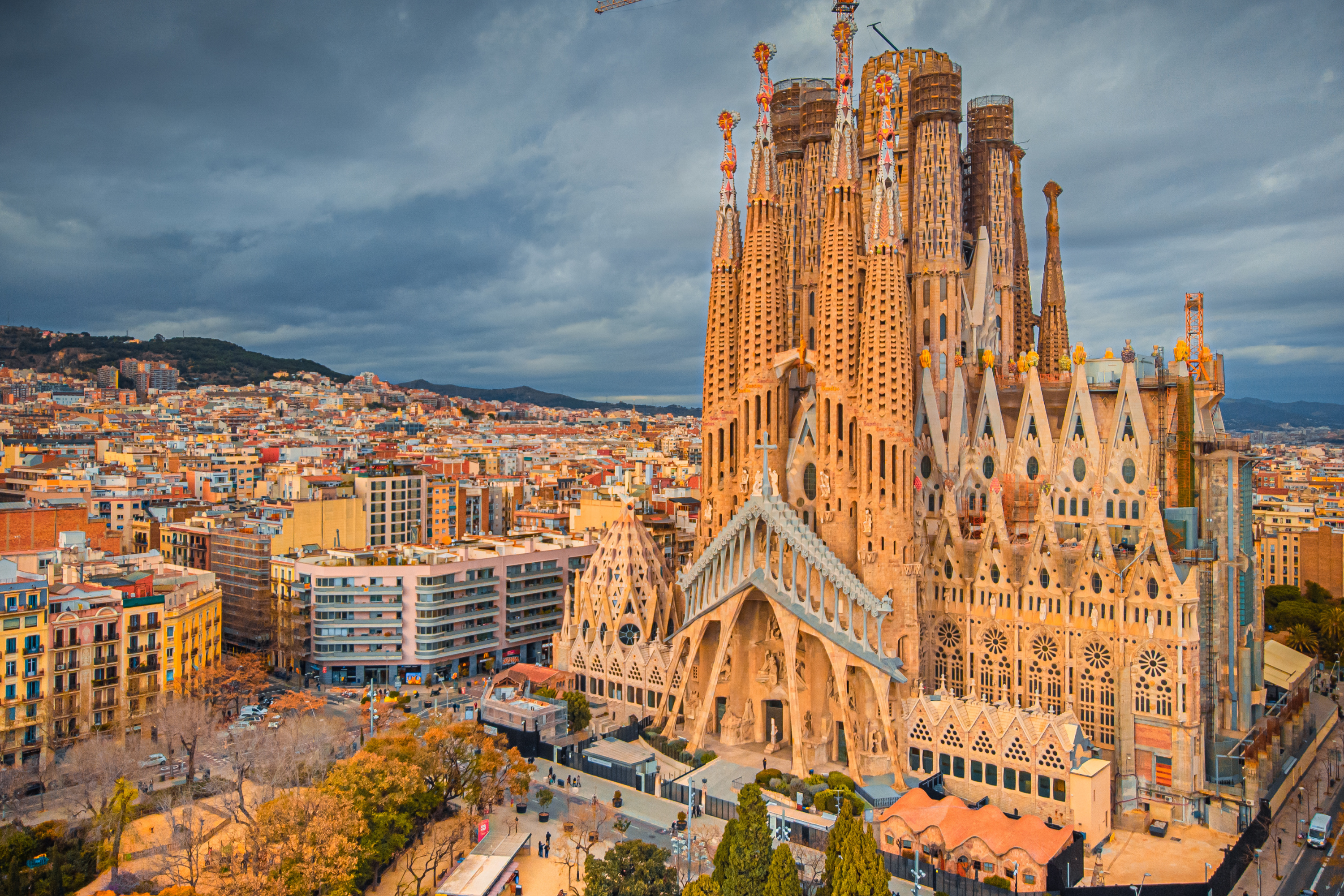 La Sagrada Família basilica spires rising above Barcelona cityscape under a cloudy sky