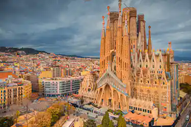 La Sagrada Família basilica spires rising above Barcelona cityscape under a cloudy sky