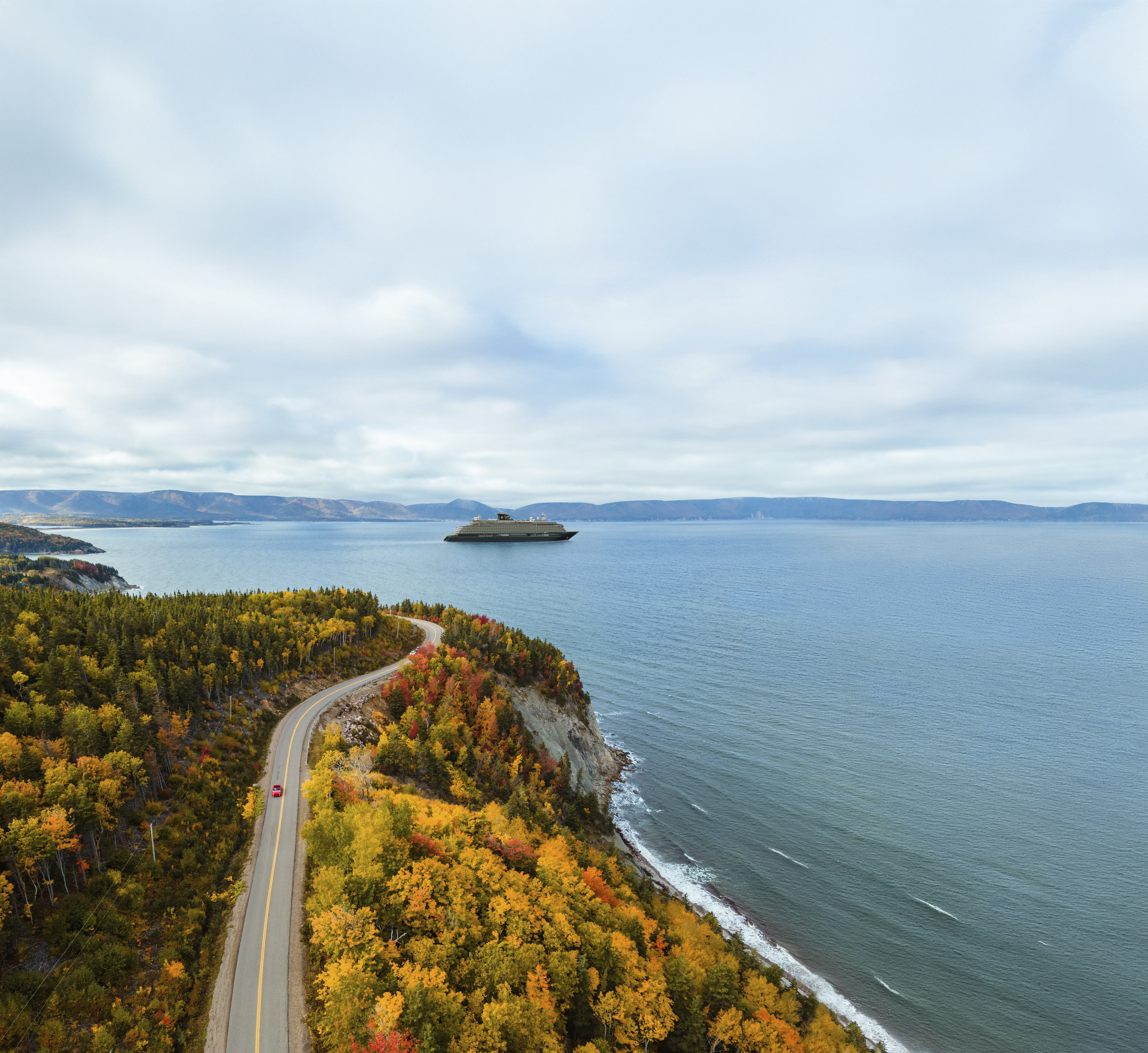 Aerial view of autumn coastline with winding road and red car, cruise ship on calm bay