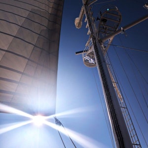 Upward view of sailboat mast, rigging and sail, sunburst and Greek flag against blue sky