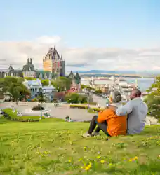 Older couple on a grassy hill, arm in arm, overlooking Château Frontenac and St. Lawrence River