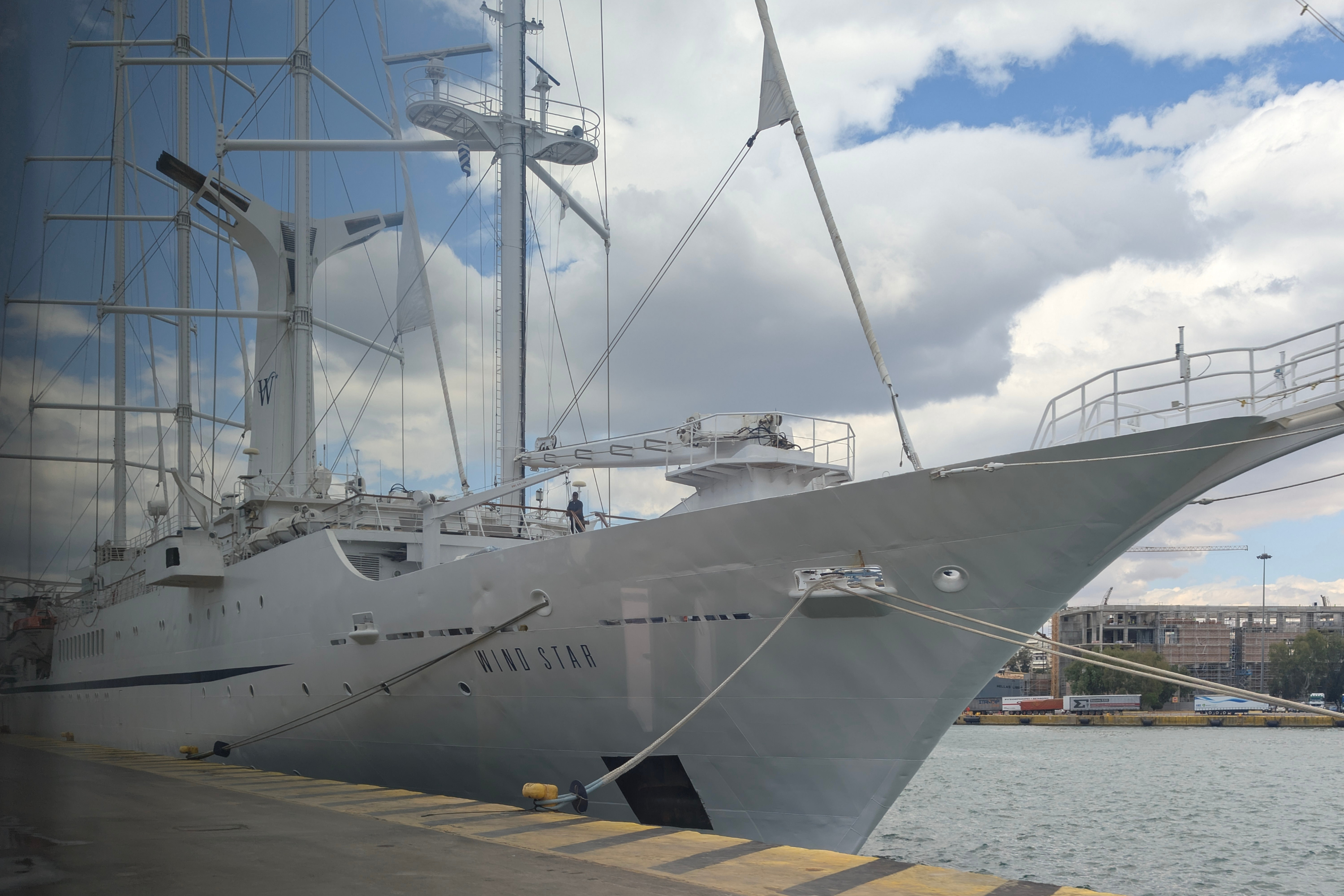 Large white sailing yacht Wind Star docked at a port, bow and masts with rigging against clouds