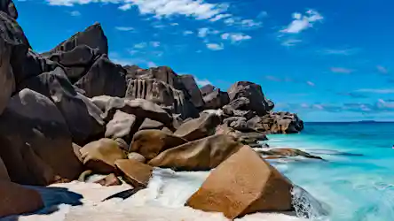 Tropical granite boulder shoreline with turquoise sea and bright blue sky